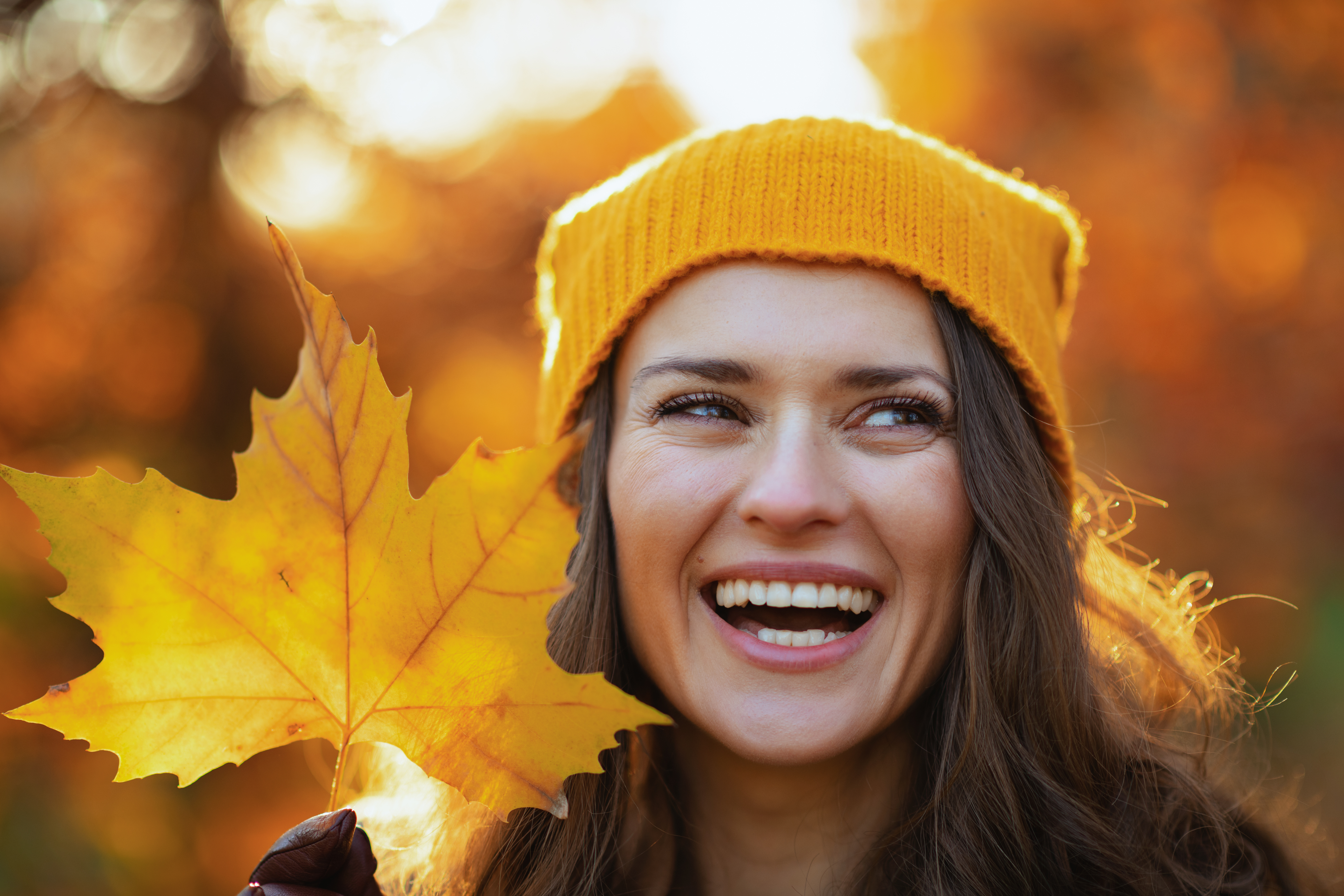 Woman smiling holding a maple leaf.