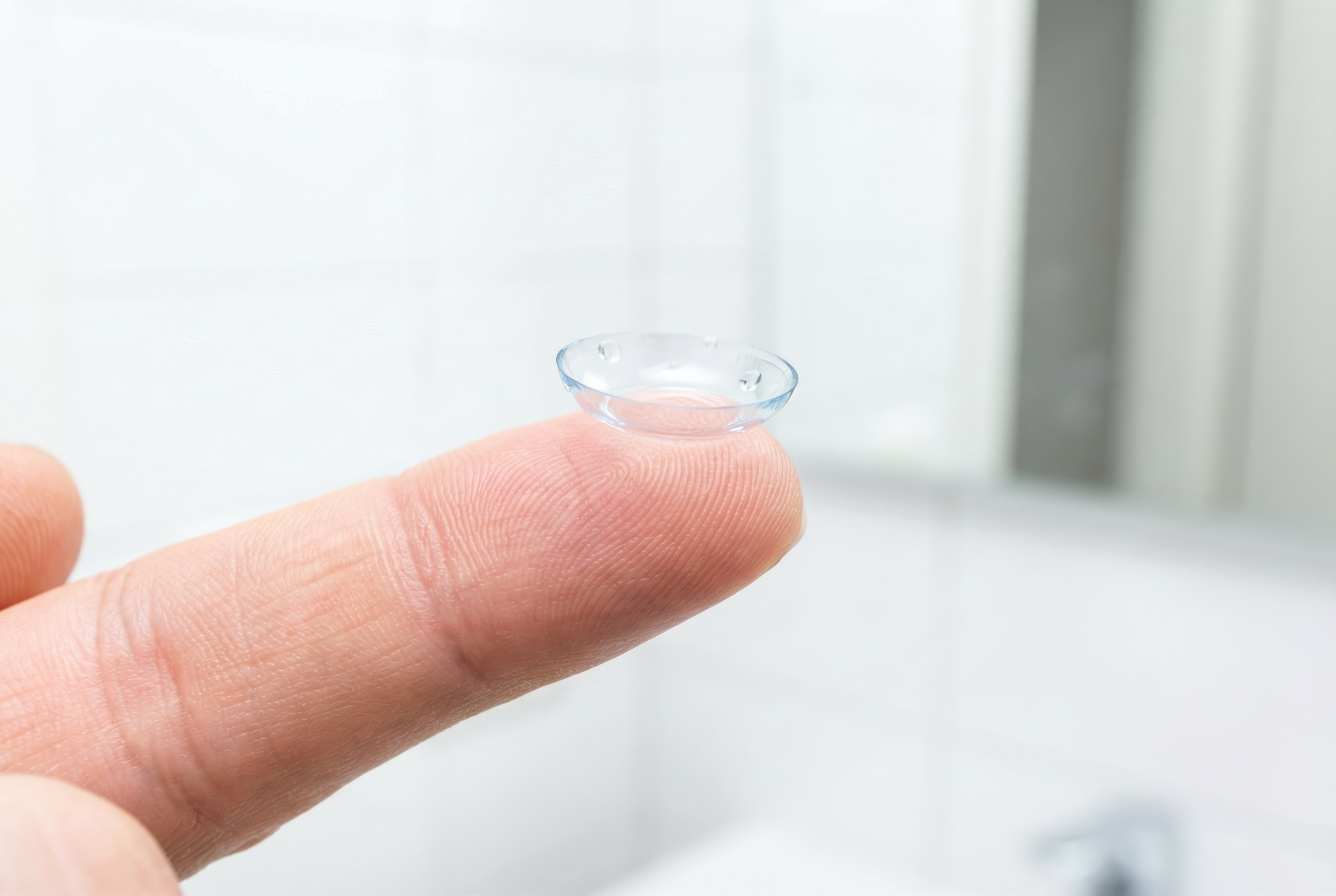 Shot of a clear soft contact lens balancing on the tip of a human finger