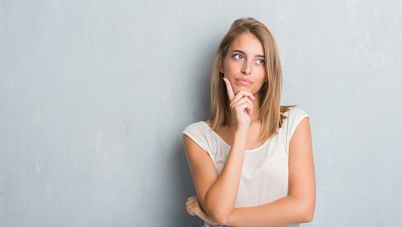 Woman looking puzzled while thinking, with a questioning expression.