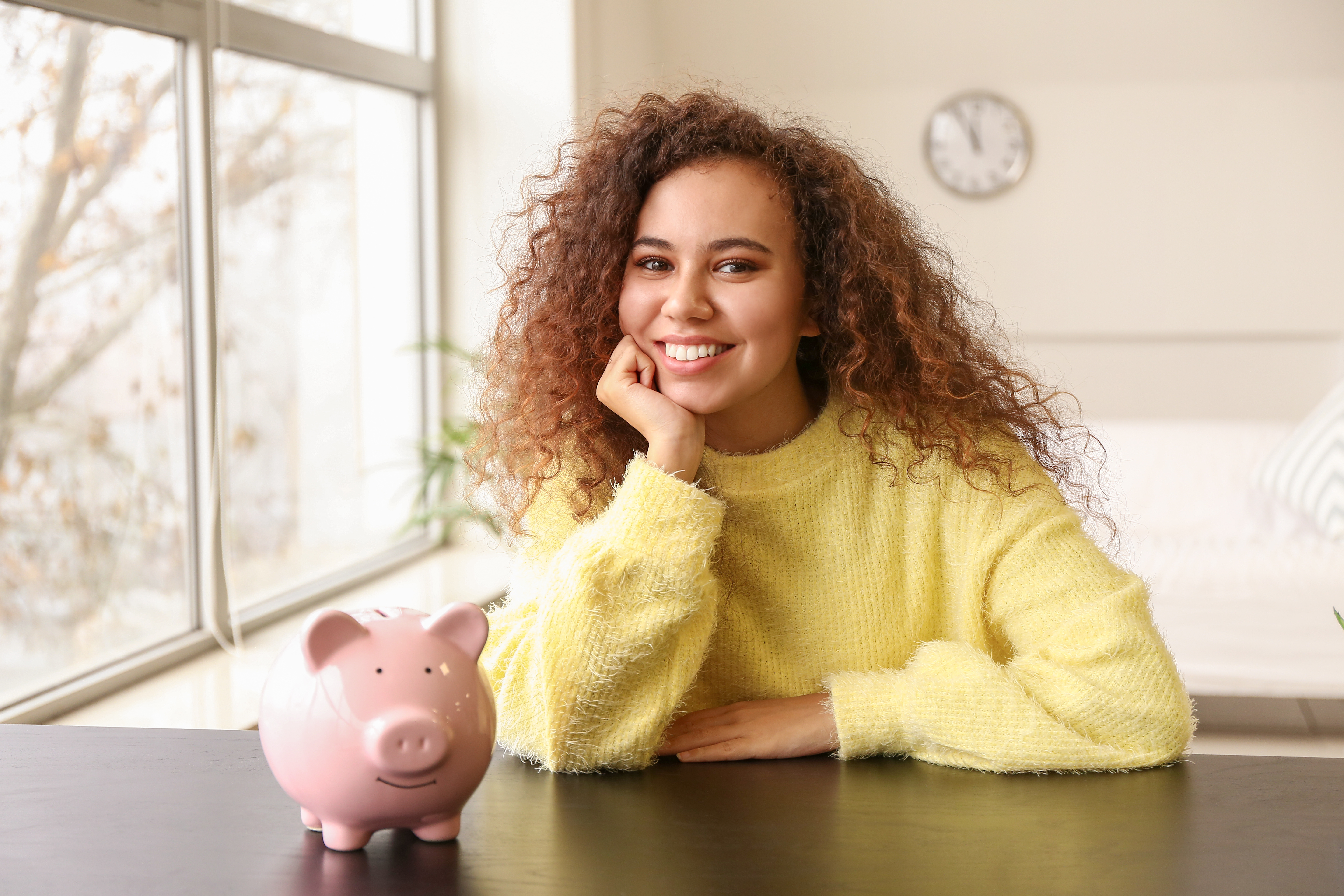 Smiling young woman saving money with a piggy bank
