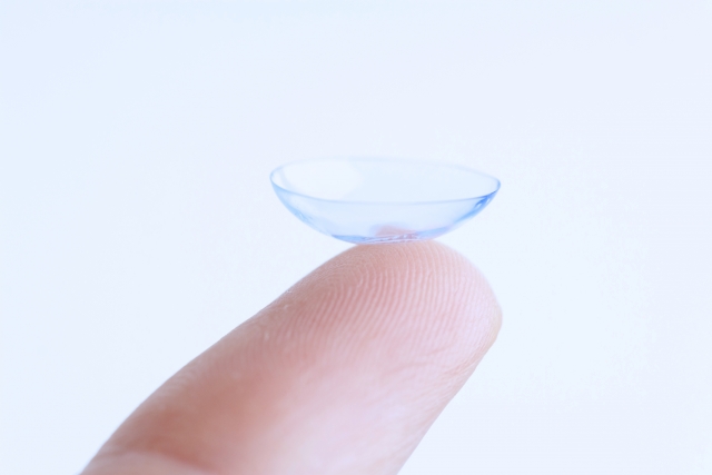Extreme close up of index finger with contact lens on top