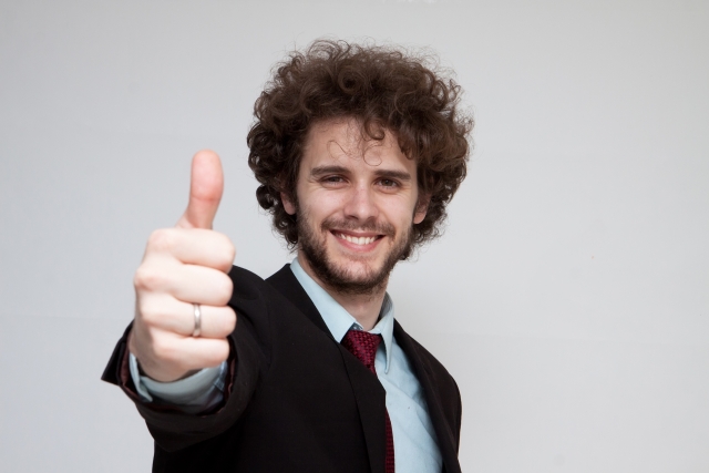 Man in suit with right hand giving thumbs up to the camera