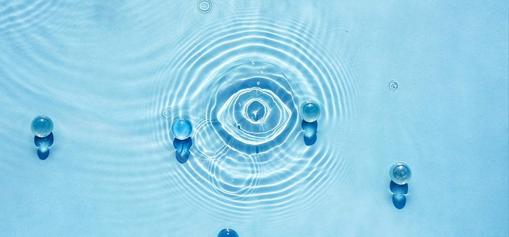Top view of droplets falling into water, rippling in an eye shape