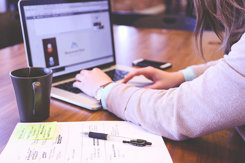 An image of a woman using a laptop on a desk