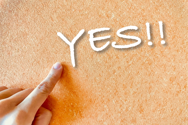 Index finger on sand background pointing to digitally added ‘YES!!’